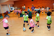 朝の自由遊びの時間にサッカーを楽しむ子どもたち。見学している子も思わずやってみたくなるような楽しい雰囲気作りを心がけながらも、時折「この場合、あのポジションに誰かが入った方がボールが回せるでしょ?」などと「TOMYO.FC」のメンバーに中村先生からアドバイする場面も